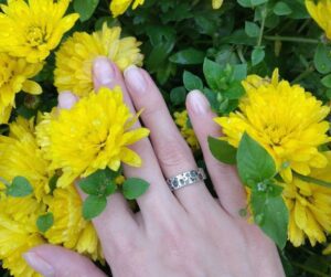 a hand with a ring on a yellow flowers