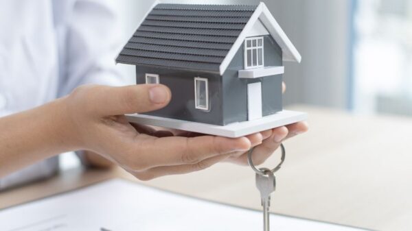 person holding a house with a key and clip board