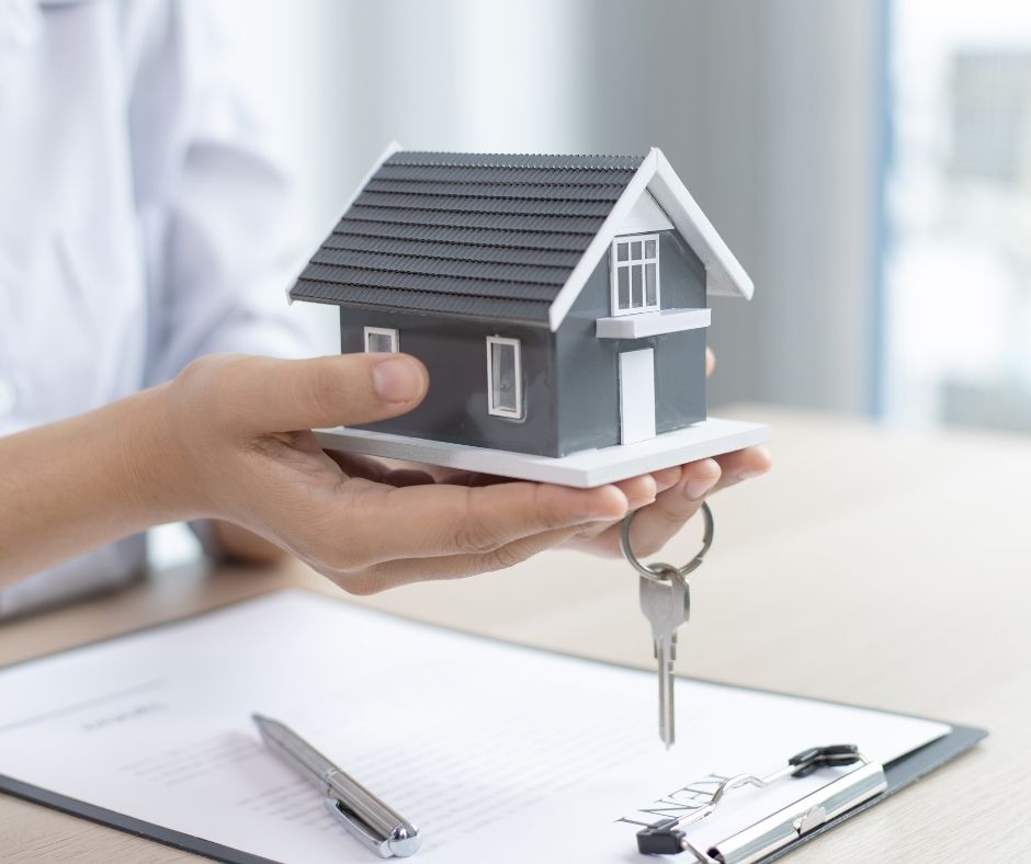 person holding a house with a key and clip board