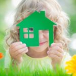 Little girl in a field of flowers holding a house in her hands