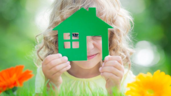 Little girl in a field of flowers holding a house in her hands