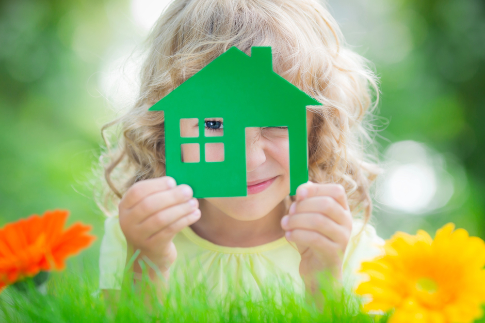 Little girl in a field of flowers holding a house in her hands