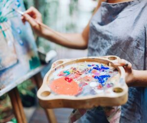 a person holding a paint tray painting on canvas