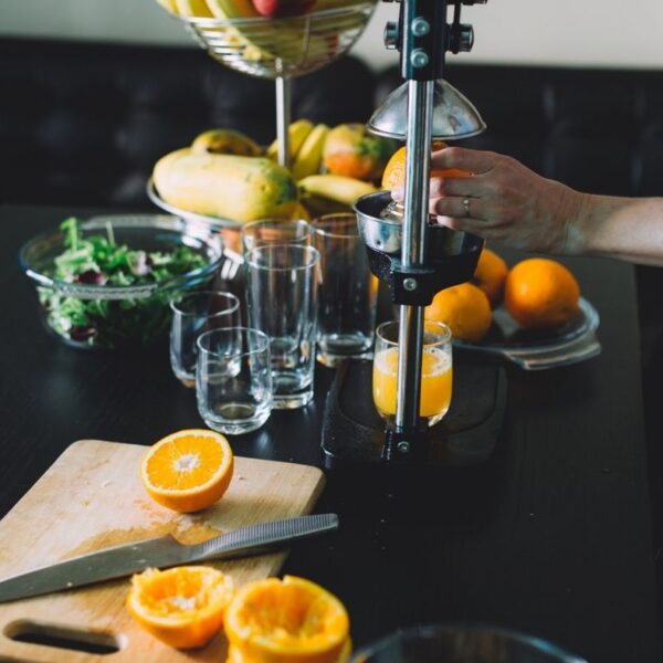 a hand squeezing orange juice into glasses