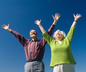 2 senior citizens with their hands up